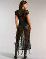 Vestido largo de encaje negro con aberturas laterales, corte ajustado y mangas cortas. Incluye un cinturón con apliques metálicos.