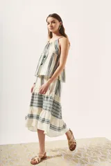 Top blanco con estampado de líneas verticales en verde y escote halter con tirantes finos.