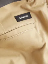 Shorts color beige confeccionados en sarga de algodón orgánico con elasticidad añadida, talle medio, corte slim, bragueta con cremallera, bolsillos en la costura lateral, bolsillos de ojal en la parte trasera y cinturón con hebilla en forma de D incluido.