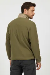Campera de poliéster color verde militar con cuello alto y cierre frontal. Presenta un bolsillo con cierre en el pecho y dos bolsillos laterales, todos en color beige.