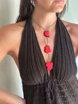 Collar largo con cadena de acero quirúrgico dorada y tres piedras irregulares de color rojo intenso unidas por eslabones ovalados de bronce o alpaca. Presenta un diseño tipo corbatín con cierre regulable.