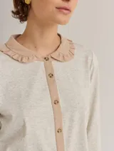 Camisa blanca de algodón con cuello redondo, manga larga y cierre frontal con botones.