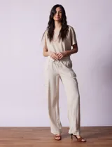 Pantalón cargo de lino color blanco, marca Marissa Olivia. Tiene pretina ancha elastizada con lazo de ajuste, bolsillos inclinados delanteros y bolsillos laterales con botón.
