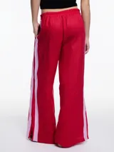 Pantalón de lino negro con elástico en la cintura, tiro medio y calce relajado. Lleva tiras en color gris aplicadas a los laterales, que quedan sueltas en la parte inferior y pueden anudarse.