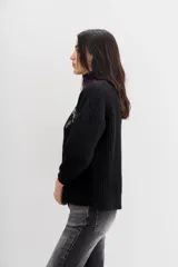 Cardigan negro de tejido de punto con ochos y terminaciones en punto rib. Presenta calce relajado, mangas largas y apliques bordados en piedras y canutillos en la parte superior del frente.