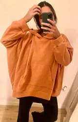Combo de canguro con capucha color naranja y pantalón de jogging negro.