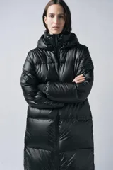 Plumífero largo negro con cuello alto y capucha ajustable con cordón elástico y stopper. Manga larga y puño interior en tejido efecto scuba. Bolsillos en delantero con interior en polar fleece. Bajo ajustable con cordón elástico y stopper. Cierre frontal con cremallera termosellada.