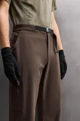 Pantalón de hombre color beige/caqui, de corte regular fit, confeccionado en tejido técnico compacto con elasticidad. Presenta cintura ajustable con cinturón a contraste, bolsillos frontales, bolsillo trasero con cierre de cremallera oculta y bolsillo cargo con cierre de cremallera oculta en la pernera.