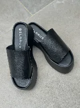 Sandalias tipo sueco con plataforma de goma negra y tira ancha de cuero con estampado animal print de vaca.