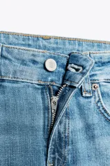 Jeans de tiro bajo con trabillas y cinco bolsillos. Bajo acampanado desde la rodilla. Cierre frontal con cremallera y botón metálico.