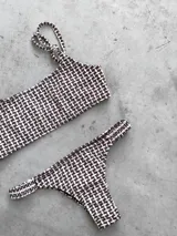 Conjunto de bikini con estampado geométrico en tonos celeste, azul, blanco, amarillo y naranja. El corpiño es bandeau con breteles regulables y lazo en la espalda. La bombacha es vedetina con frunce elástico en los costados.