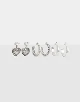 Set de tres pares de aros plateados con pasantes: un par de aros colgantes con forma de corazón, un par de aros tipo argolla con diseño trenzado y un par de aros tipo argolla lisos.