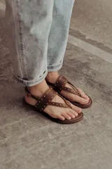 Sandalias marrones de cuero con tiras, microtachas doradas y hebilla lateral.