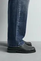 Bota de cuero negra con cierre de cremallera lateral, plantilla de cuero, horma cuadrada y tacón bajo.