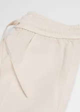 Pantalón de algodón color crudo, de corte recto, tiro medio, con cintura elástica ajustable con cordón y dos bolsillos de parche laterales.
