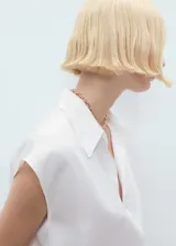 Camisa blanca sin mangas con cuello camisero y cierre frontal con botones.