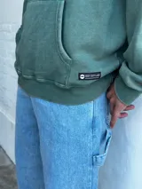 Buzo canguro verde con capucha y cordones ajustables.