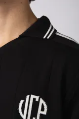 Remera tejida color crudo con cuello tipo chomba en V, mangas cortas con rayas negras y estampado con letras en el frente. Confeccionada en hilado de algodón.