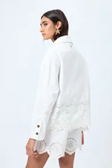 Sobrecamisa blanca de algodón con cuello camisero, botones marrones y detalles de encaje calado en el ruedo.