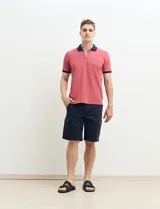 Remera polo blanca de piqué con cuello y puños en azul marino. Tiene tapeta de dos botones y bolsillo de parche en el pecho.