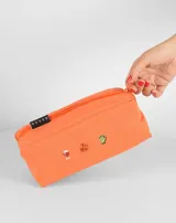 Neceser naranja de tela con cierre superior y logo de la marca en etiqueta negra. Presenta bordados de emojis: copa de vino, fuegos artificiales y mano verde.