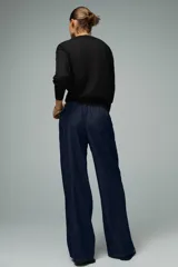 Pantalón de jean azul oscuro, de tiro alto y pierna ancha, con cintura elástica ajustable con cordones y bolsillos delanteros.
