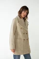 Abrigo de lana color beige con cuello solapa y manga larga. Cierre frontal cruzado doble con botones dorados. Bolsillos delanteros plaqué y forro al tono. Tela 100% lana fina sin teñir, diseñada exclusivamente por Don Baez. Hecho 100% en Uruguay.