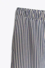 Pantalón de tiro medio con cintura elástica y bolsillos laterales ocultos en costura. Pierna ancha y diseño a rayas verticales azules y blancas.
