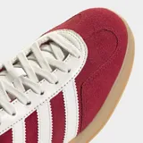 Championes Adidas Gazelle Indoor, color rojo oscuro (borgoña) con puntera de gamuza, tres franjas y talón en cuero sintético blanco, y suela de goma color caramelo.