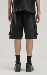 Bermuda negra de algodón rústico con calce oversize, elástico en la cintura y bolsillos con cierre.