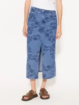 Pollera midi de denim celeste con estampado de limones y hojas en azul oscuro. Tiene corte recto, tiro alto y abertura frontal.