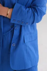 Blazer azul de lino, con solapa de muesca, cierre frontal con botones y bolsillos laterales.