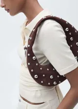 Cartera hobo marrón de gamuza con tachas plateadas de diferentes tamaños.