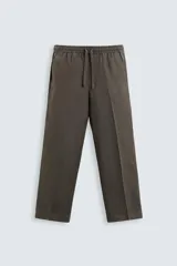 Pantalón de lino color marrón oscuro, de corte recto y relaxed fit. Tiene cintura elástica ajustable con cordón, bolsillos frontales y traseros de parche.