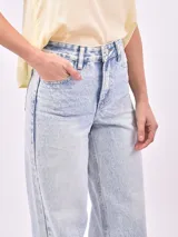 Jean de mezclilla celeste con lavado ácido y efecto desgastado. Modelo de tiro alto y corte ancho (wide leg) con ruedo deshilachado.