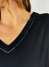 Remera azul de corte recto con cuello en V y detalle de tachas plateadas en el borde del escote.