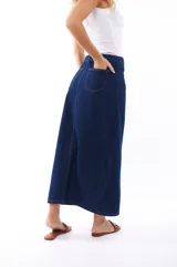 Falda midi de jean azul oscuro, con corte recto, abertura frontal y cierre con botones metálicos.