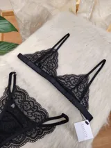 Conjunto de lencería negro de encaje, compuesto por un bralette con breteles regulables y una tanga regulable con corte media less y entrepierna de algodón.