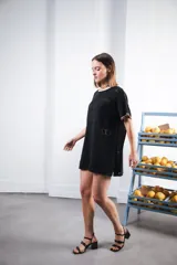 Vestido corto negro con patrón calado cuadrado, cuello redondo y mangas cortas con terminaciones a contratono en blanco.