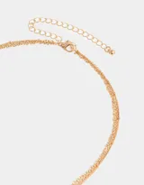 Collar corto dorado multicadena con dijes místicos, piedra amatista y cierre de mosquetón.