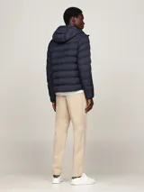 Campera Tommy Hilfiger acolchada color azul marino, con capucha fija ajustable con cordón, cierre de cremallera frontal, dos bolsillos laterales y parche engomado con el logo de la marca en la manga.