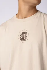 Remera oversize blanca de algodón con un pequeño estampado circular en el pecho que simula un cerebro o un diseño abstracto en espiral, en color negro.