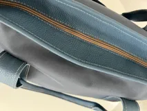 Bolso tote negro de lona con apliques de cuero y doble asa de mano.