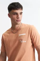 Remera color durazno de manga corta con cuello redondo y estampado frontal con texto en recuadro.