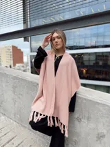 Ruana rosa pastel tejida en acrílico con flecos.