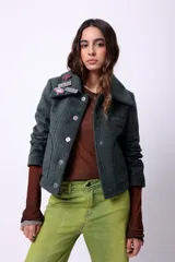 Campera corta de poliéster texturizado color verde oscuro, con cuello camisero, cierre frontal con botones a presión, bolsillos delanteros y forro interior. Incluye pins decorativos.