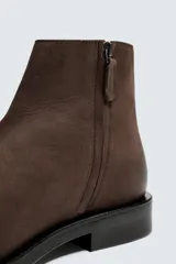 Botín marrón de piel con acabado serraje, cierre de cremallera lateral, plantilla de piel, horma cuadrada y suela a contraste con ligero tacón.