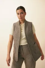 Chaleco color beige, entallado, con solapa, bolsillos plaqué y terminaciones envivadas.