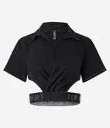 Camisa corta negra con cuello camisero, mangas cortas y aberturas laterales con elástico con letras blancas.
