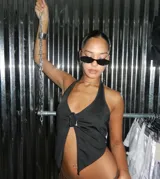 Top negro con escote halter y abertura frontal que se cierra con una hebilla metálica. El diseño es asimétrico y ajustado al cuerpo.